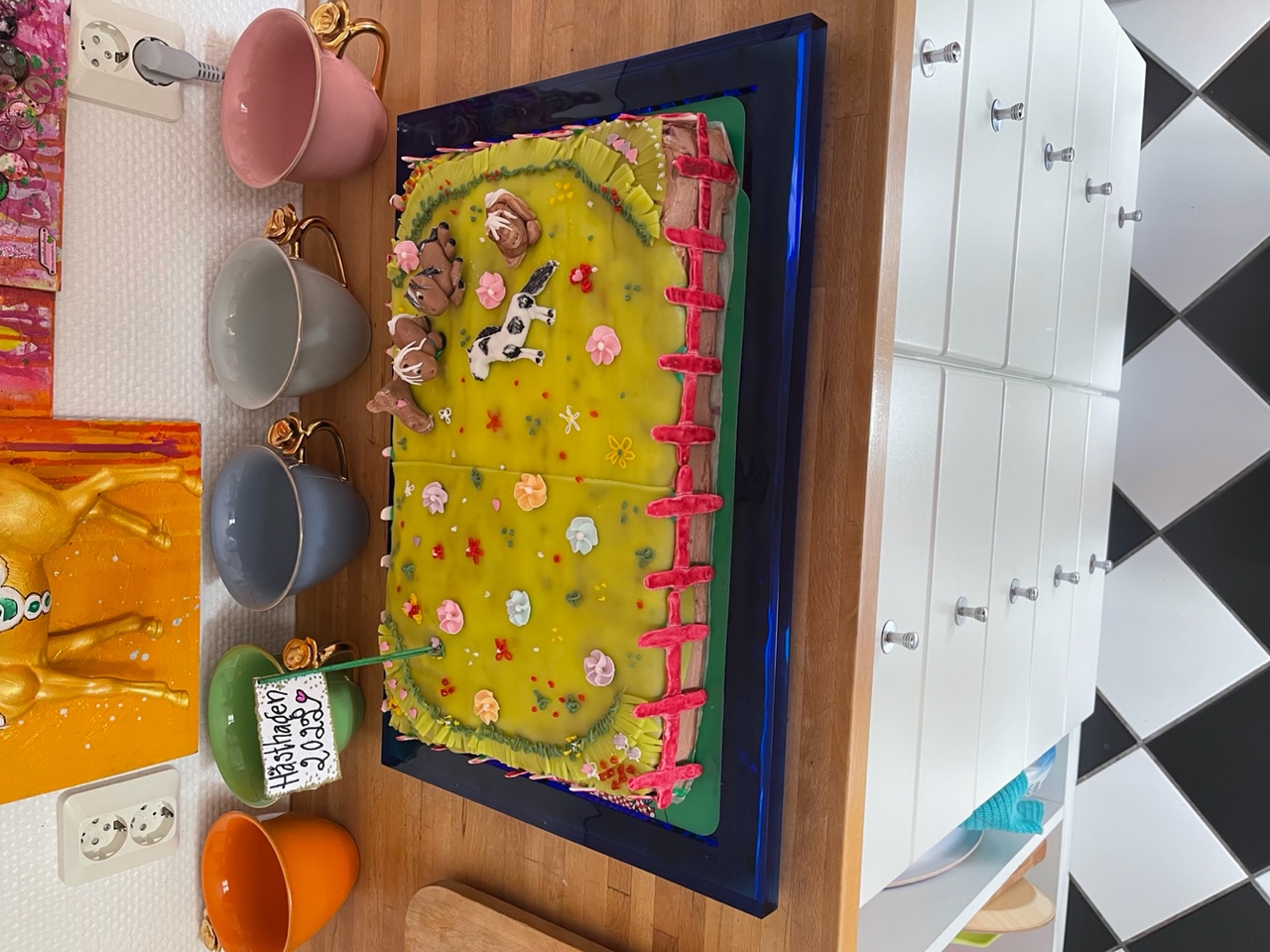 Tårta dekorerad som en hästhage med blommor, hästar och staket.