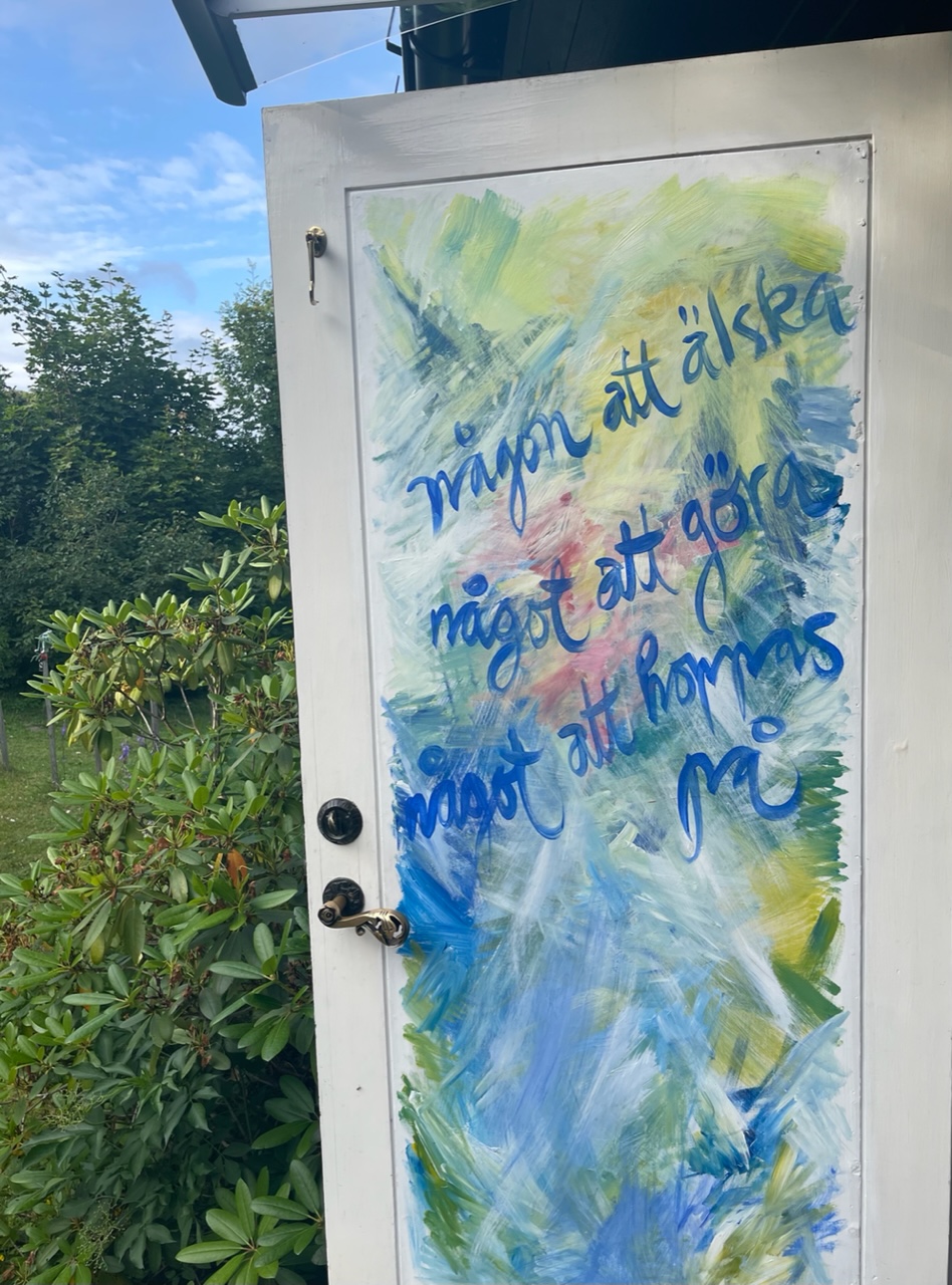 Dörr med målad som en tavla med texten "någon att älska, något att göra, något att hoppas på" 