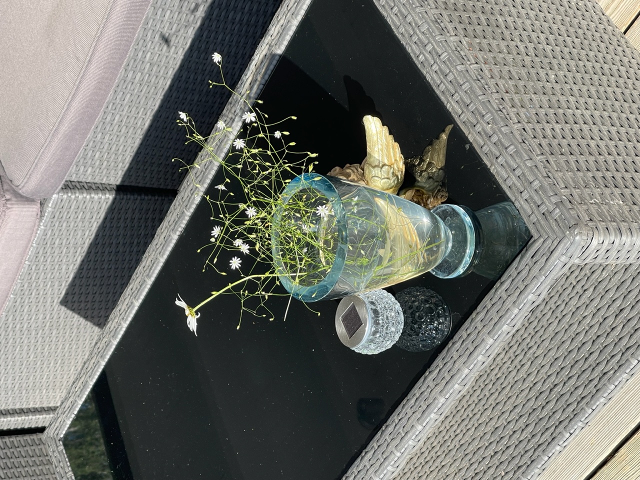 Blommor i en gladvas på ett ute-glasbord