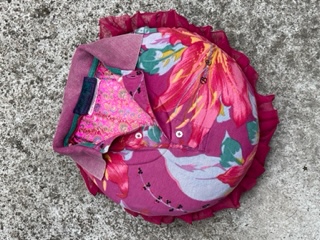 Rosa-röd rund kudde med överdrag sytt av en pikétröja