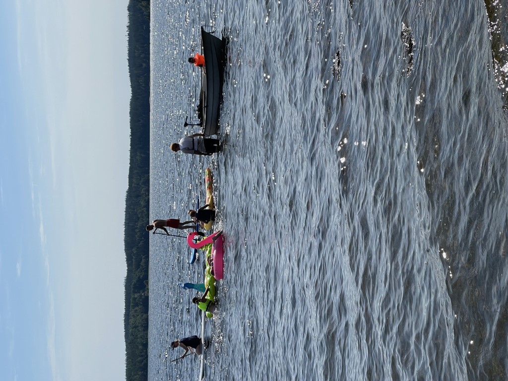 Personer på SUPar, en båt och vattenleksaker på sjön